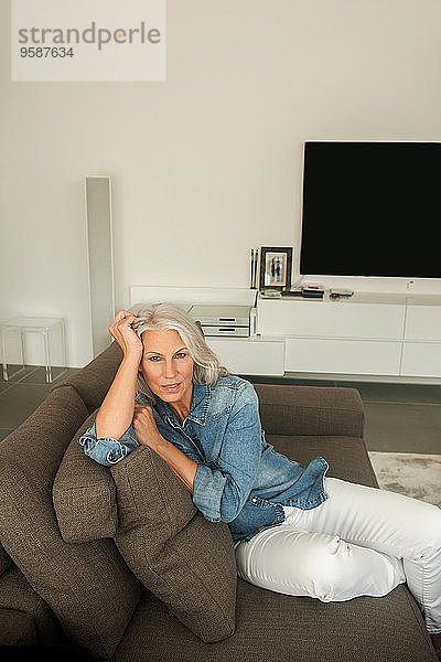 Porträt einer reifen Frau auf der Couch im Wohnzimmer