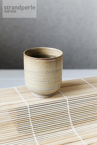 Tasse grüner Tee auf Bambusmatte