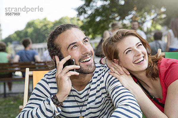 Deutschland  Berlin  Junges Paar im Park  mit Smartphone