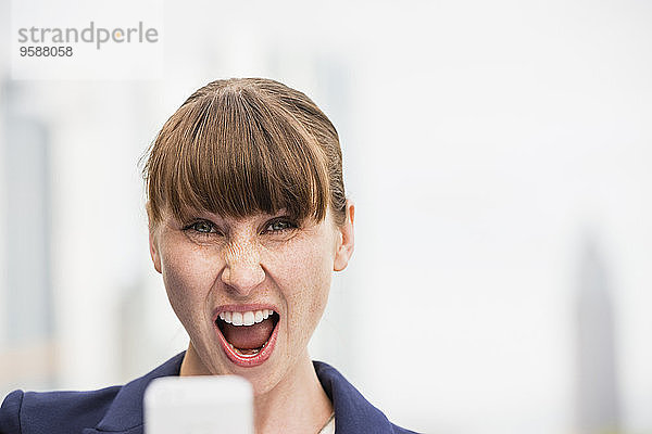 Portrait einer schreienden Geschäftsfrau mit Smartphone