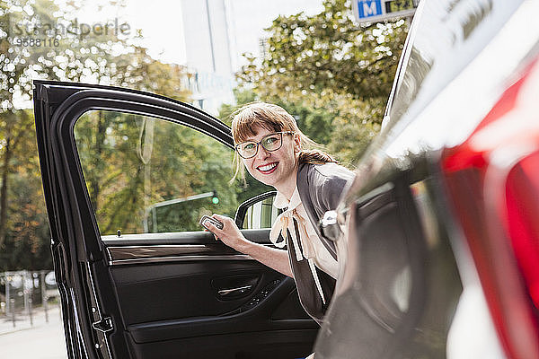 Porträt einer lächelnden Geschäftsfrau beim Aussteigen aus dem Auto