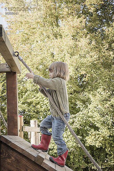 Kleines Mädchen klettert auf Spielplatzgeräte