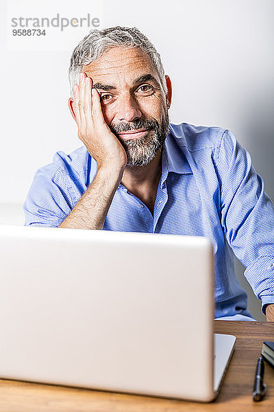 Porträt eines lächelnden Geschäftsmannes mit Laptop in seinem Home Office