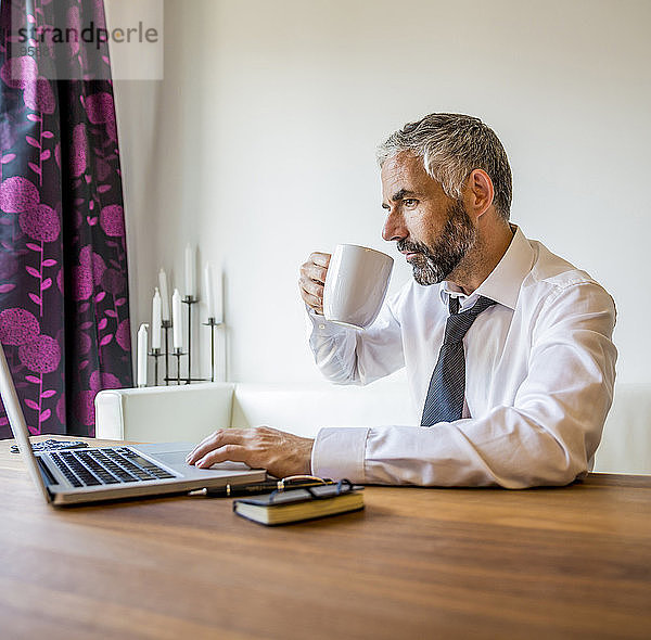 Porträt eines Geschäftsmannes  der zu Hause arbeitet und Kaffee trinkt.