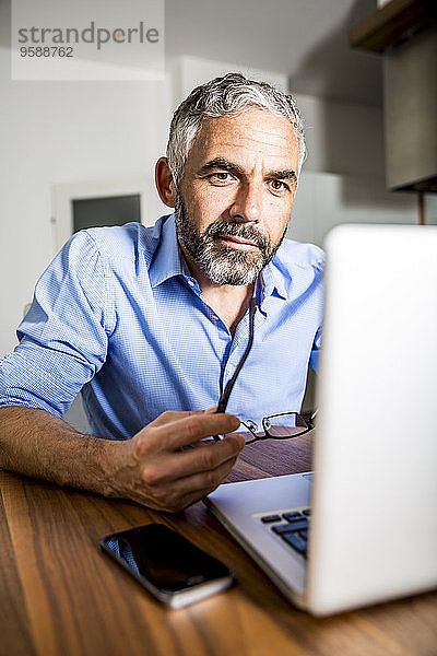 Portrait eines Geschäftsmannes  der mit dem Laptop im Home-Office arbeitet