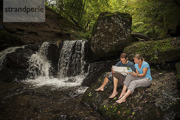 Deutschland  Rheinland-Pfalz  Moselsteig  Ehrbachklamm  Paar Lesekarte am Wasserfall