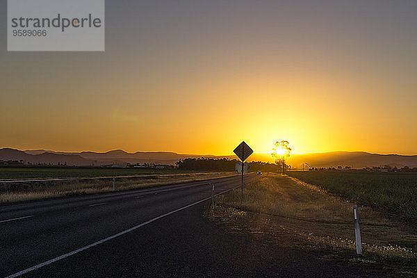 Australien  Queensland  Straße mit Bergkette bei Sonnenaufgang
