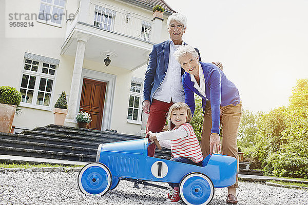 Deutschland  Hessen  Frankfurt  Seniorenpaar mit Enkelin sitzend Tretauto