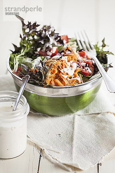 Schüssel mit gemischtem Salat und Glas Joghurtsalatdressing