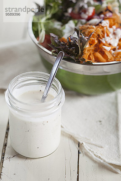 Schüssel mit gemischtem Salat und Glas Joghurtsalatdressing