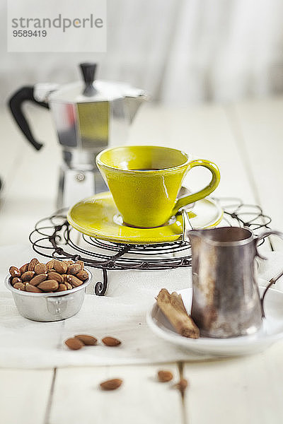 Tasse Kaffee auf Kühlrost  Schale mit Mandeln und Milchkanne