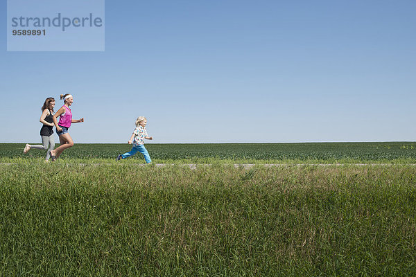 Drei Leute laufen durchs Feld