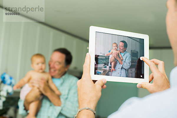 Über der Schulter Porträt von Großvater und Enkelin auf digitalem Tablett im Wohnzimmer aufgenommen