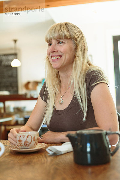 Mittlere erwachsene Frau trinkt Tee im Landhauscafé