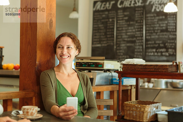 Mittlere erwachsene Frau mit Smartphone im Country Store Cafe