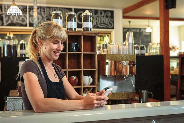 Verkäuferin SMS auf dem Smartphone im Country Store Cafe
