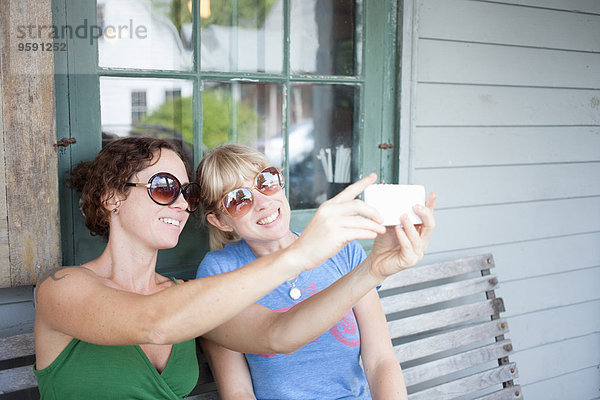 Zwei erwachsene Frauen nehmen Smartphone Selfie auf der Veranda