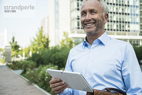Lächelnder Geschäftsmann mit digitalem Tablett im Freien