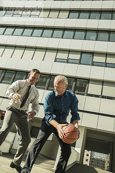 Zwei Geschäftsleute beim Basketball vor dem Bürogebäude