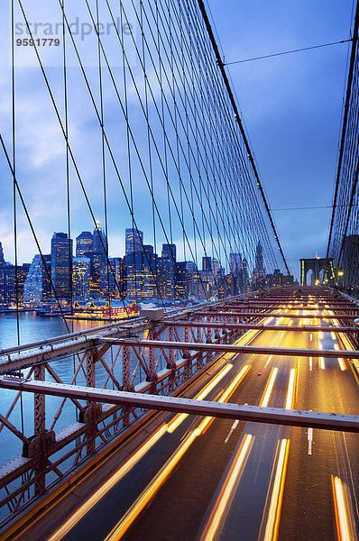 Brooklyn Bridge mit Verkehr bei Dämmerung und Wolkenkratzern in der Innenstadt  New York City  USA
