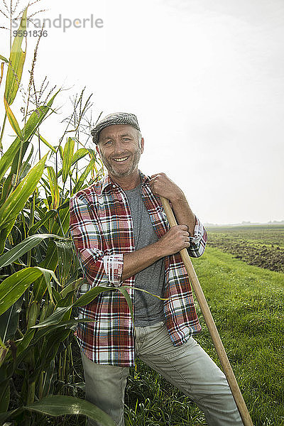 Porträt eines lächelnden Bauern neben einem Maisfeld