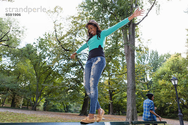 Frau beim Balancieren auf dem Geländer im Park