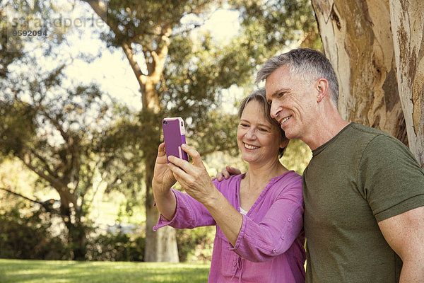 Reife Paare mit Touchscreen auf dem Smartphone im Park