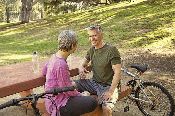 Ein reifes Radfahrerpaar macht eine Pause auf dem Picknicktisch im Park.