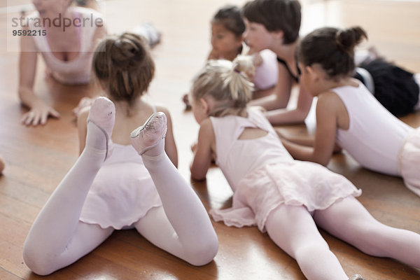 Kinder liegen auf dem Boden und üben Ballett in der Ballettschule.