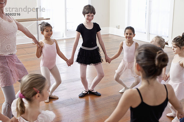 Kinder und Lehrer im Kreis üben Ballett in der Ballettschule