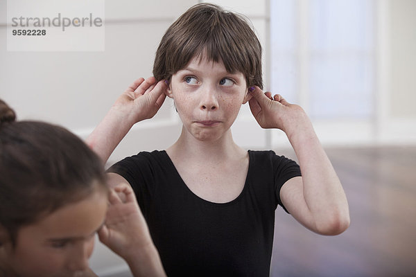Mädchen mit haltenden Ohren  das in der Ballettschule ein Gesicht zieht.