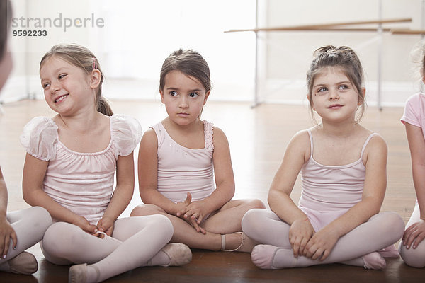 Mädchengruppe in der Ballettschule auf dem Boden sitzend