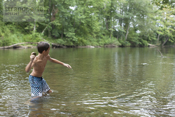 Jugendlicher Junge  der Steine in River  Kanton  North Carolina  USA abschöpft