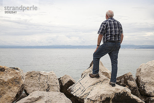 Slowenien  Piran  Mann auf Felsen am Wasser mit Blick auf den Horizont