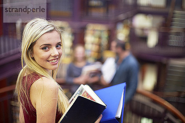 Porträt einer lächelnden Studentin in einer Bibliothek