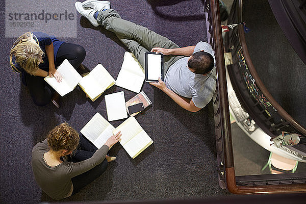 Drei Schüler lernen in einer Bibliothek