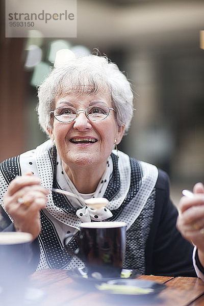 Porträt einer älteren Frau  die sich in einem Straßencafé ausruht.