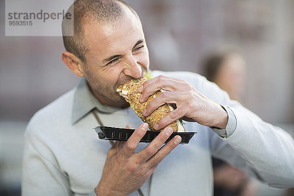 Porträt eines Geschäftsmannes  der mittags ein Sandwich isst