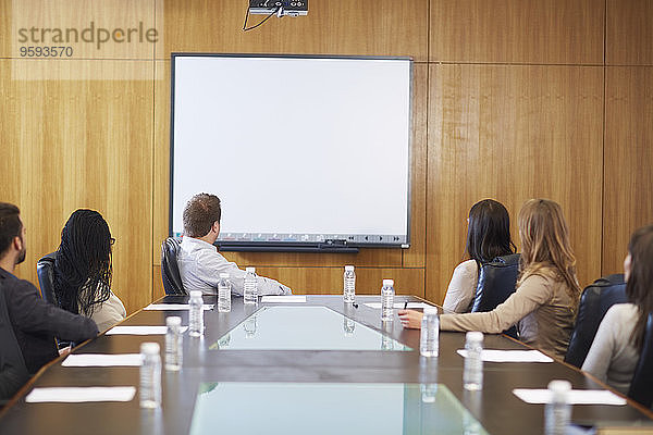 Gruppe von Geschäftsleuten  die ein leeres Whiteboard im Sitzungssaal anschauen