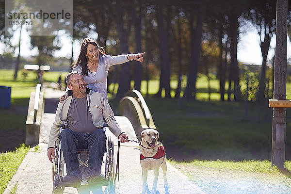 Frau mit Mann im Rollstuhl und Hund im Park