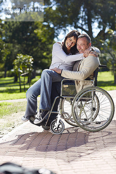 Frau umarmt Mann im Rollstuhl