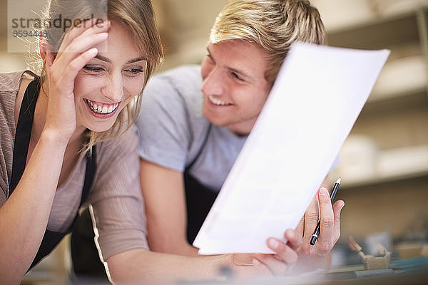 Lächelndes Paar mit Papier in einer Werkstatt