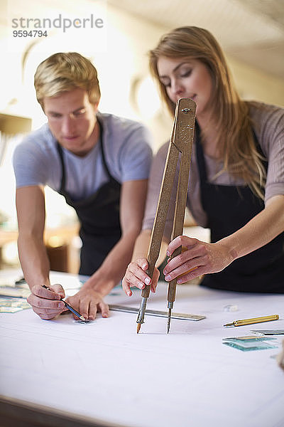 Paar in einer Werkstatt zur Herstellung von Glasmalerei mit großem Zirkel