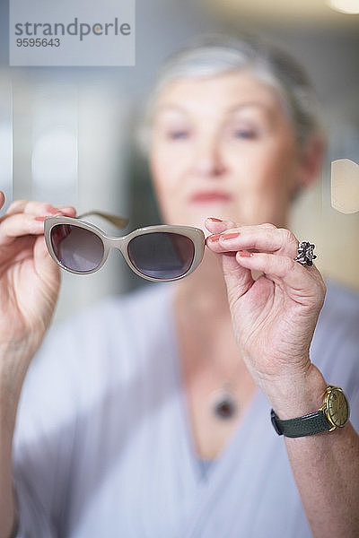 Seniorin beim Optiker beim Anprobieren der Sonnenbrille