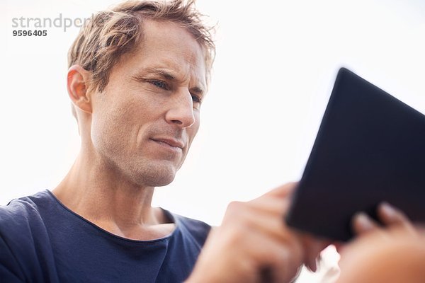 Reifer Mann mit Tablet-Computer gegen den klaren Himmel