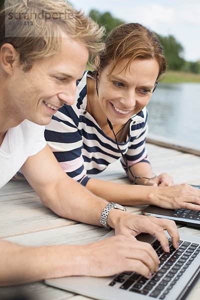 Glückliche reife Frau mit Mann mit Laptop am Pier