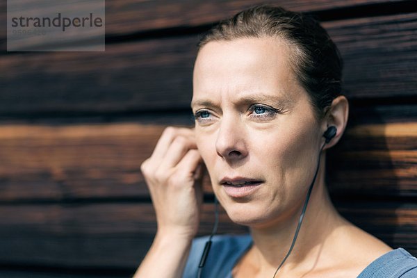 Reife Frau mit Freisprecheinrichtung außerhalb der Blockhütte