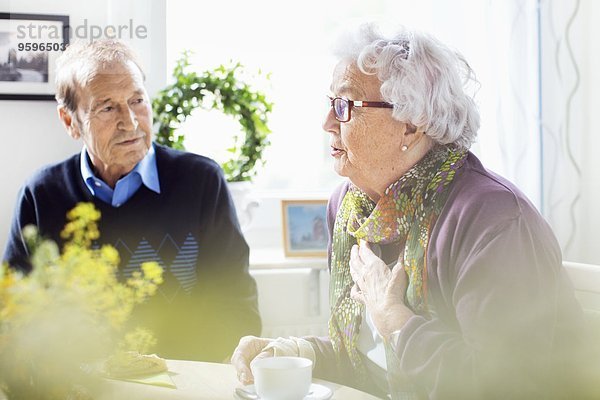 Seniorin im Gespräch mit Freunden am Frühstückstisch im Pflegeheim