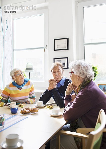 Senioren diskutieren am Frühstückstisch im Pflegeheim