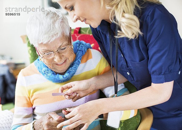 Abheften der Fingernägel der Seniorin im Pflegeheim
